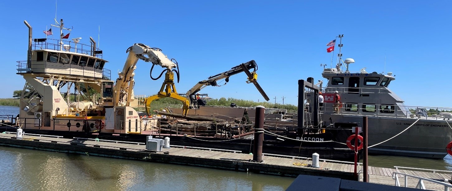 two boats side by side with machinery lifting logs out of the water